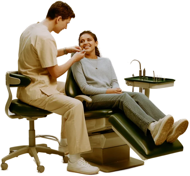 An orthodontist adjusting braces on a smiling teenage patient in the chair